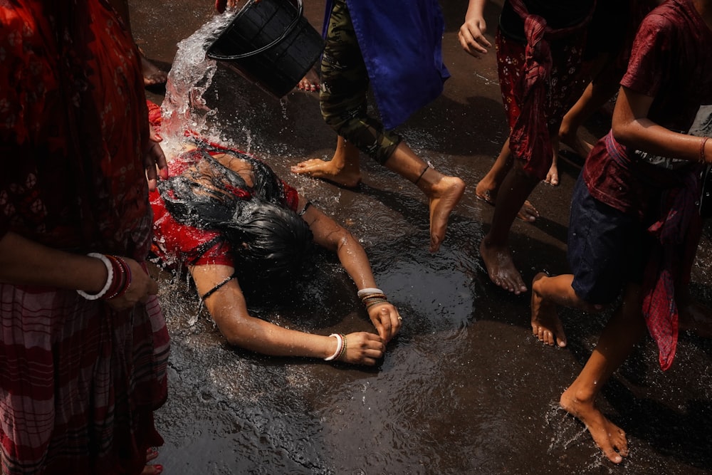 a group of people standing around a woman laying on the ground