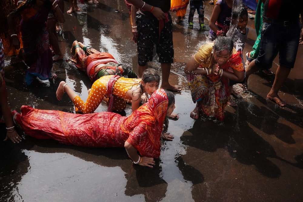 a group of people standing around a woman laying on the ground