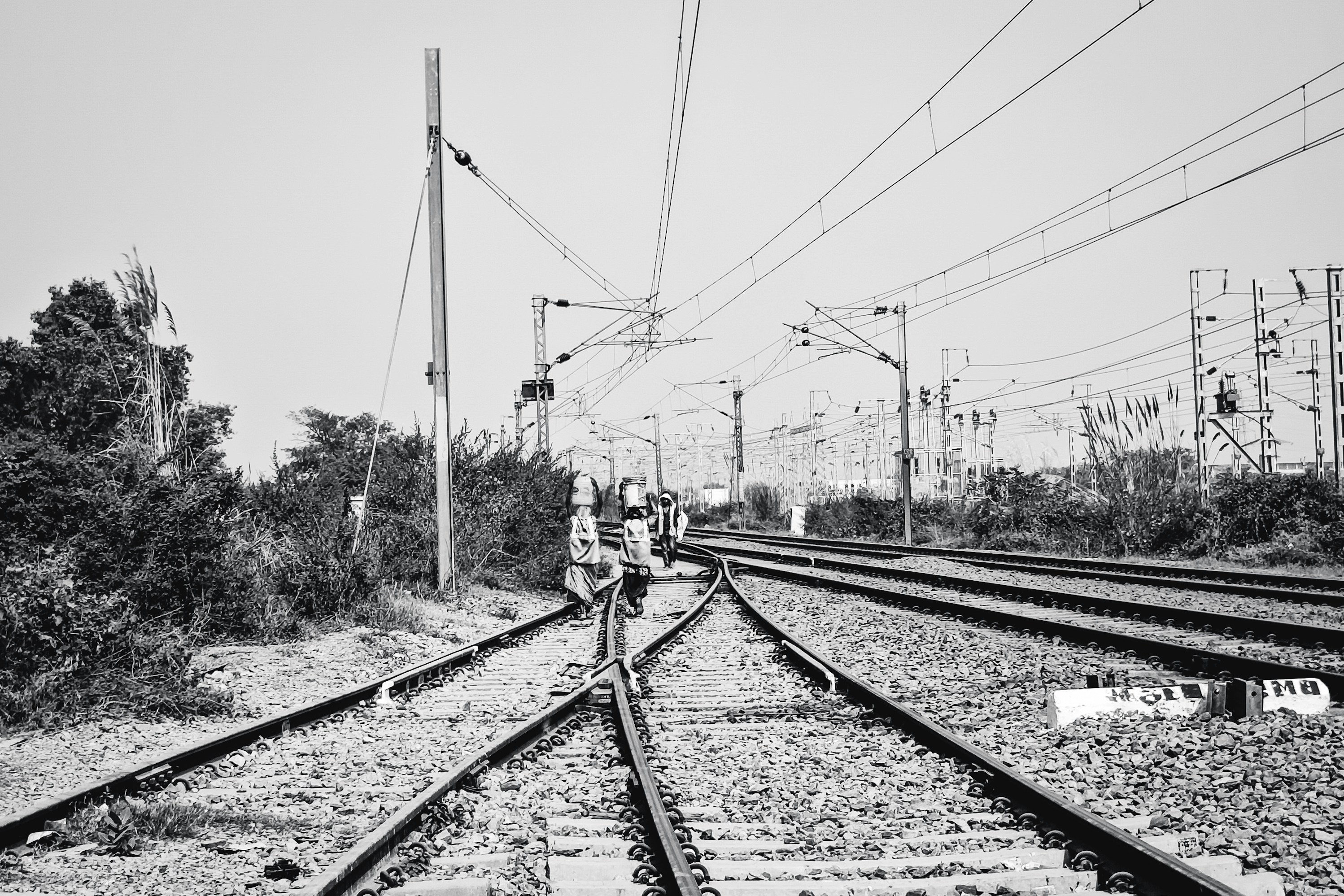 Black and white photo of people walking on train track