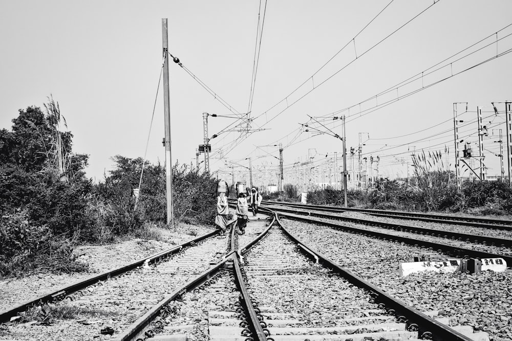 a black and white photo of people walking on a train track