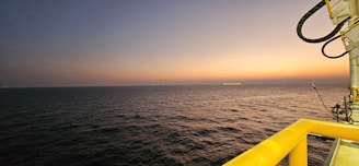 A panoramic view of an offshore platform surrounded by calm blue sea at sunset.