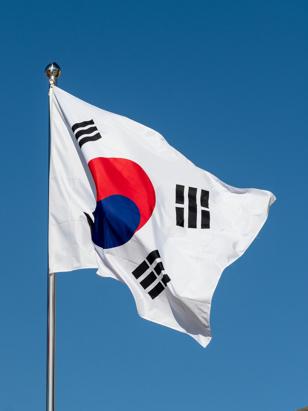 a korean flag flying in the wind with a blue sky in the background