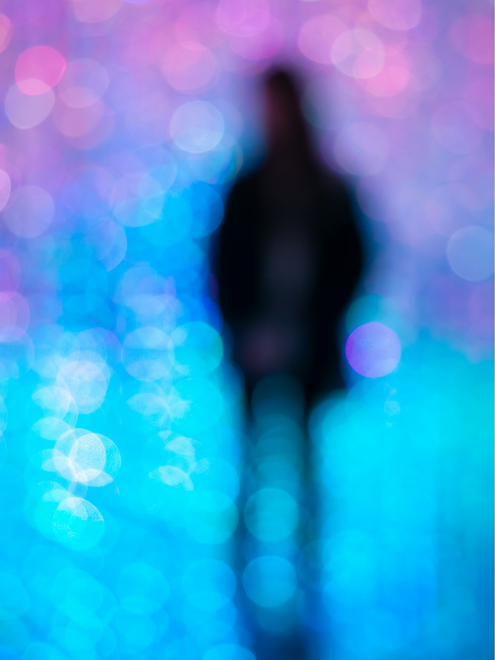 a blurry image of a person standing in front of a blue and pink background