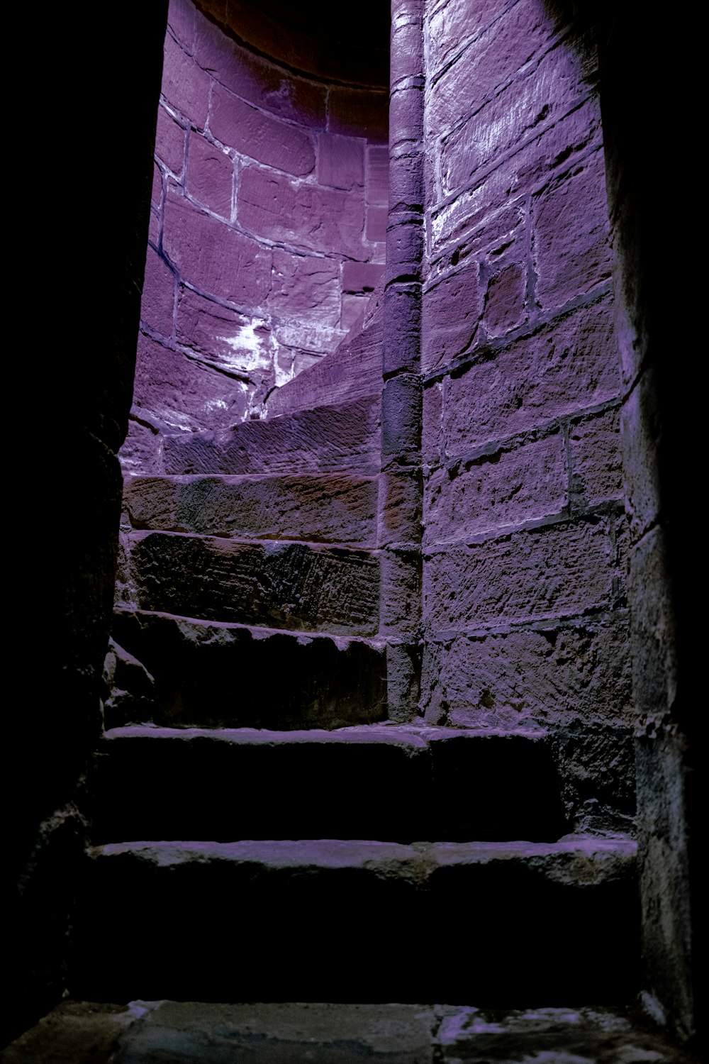 a stone stairway with a purple light coming through it