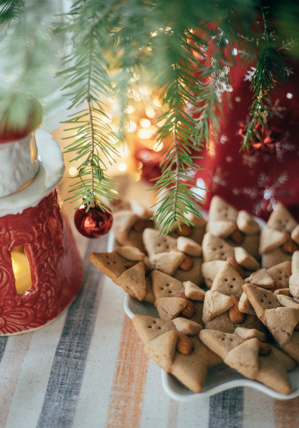 a close up of a plate of cookies near a christmas tree