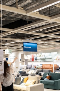 a woman holding a sign in a furniture store