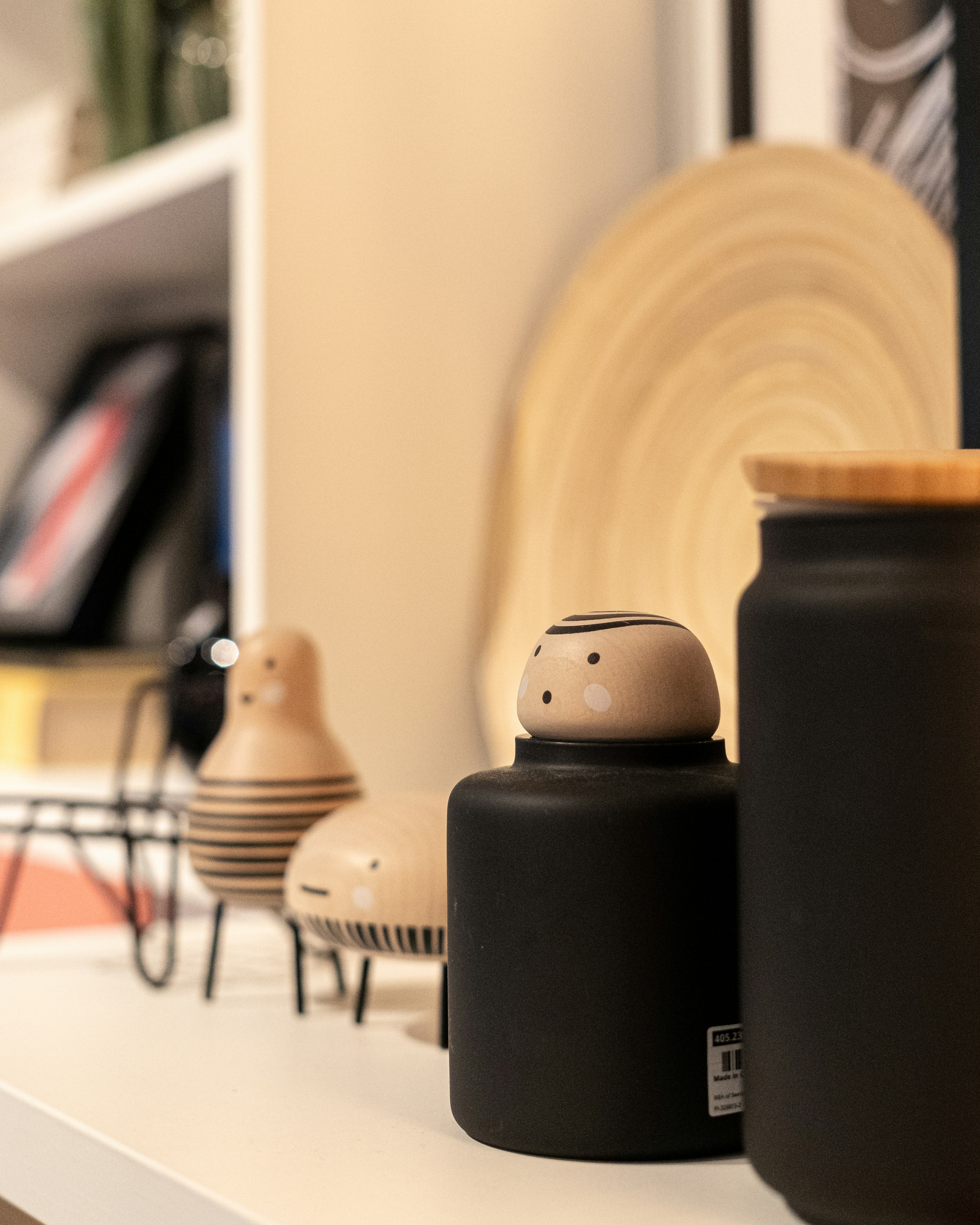 a couple of black vases sitting on top of a white shelf
