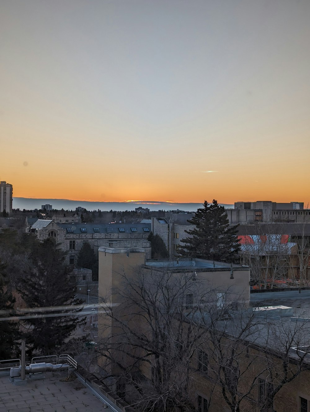 the sun is setting over a city with tall buildings