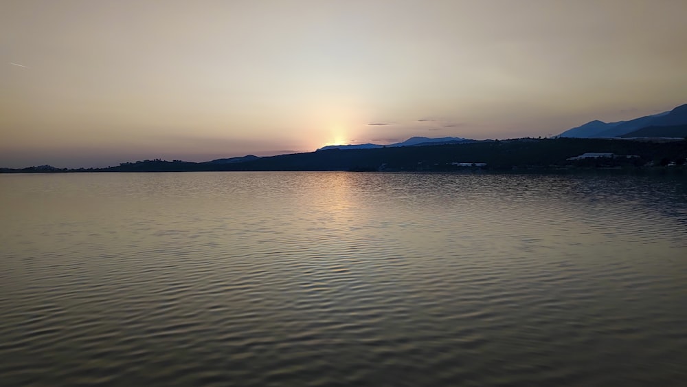 a body of water with a sunset in the background