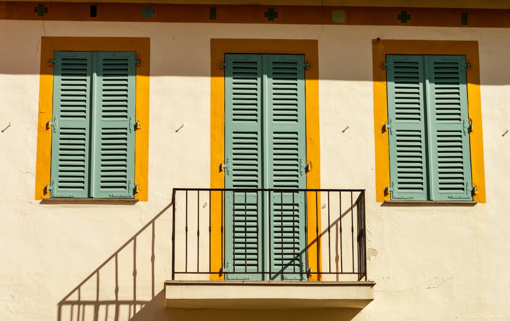 a white building with blue and yellow shutters and a balcony