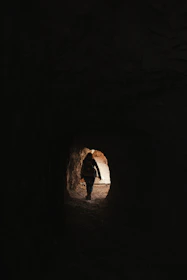 A man walking from shadowed woods into bright golden light, symbolizing transformation.