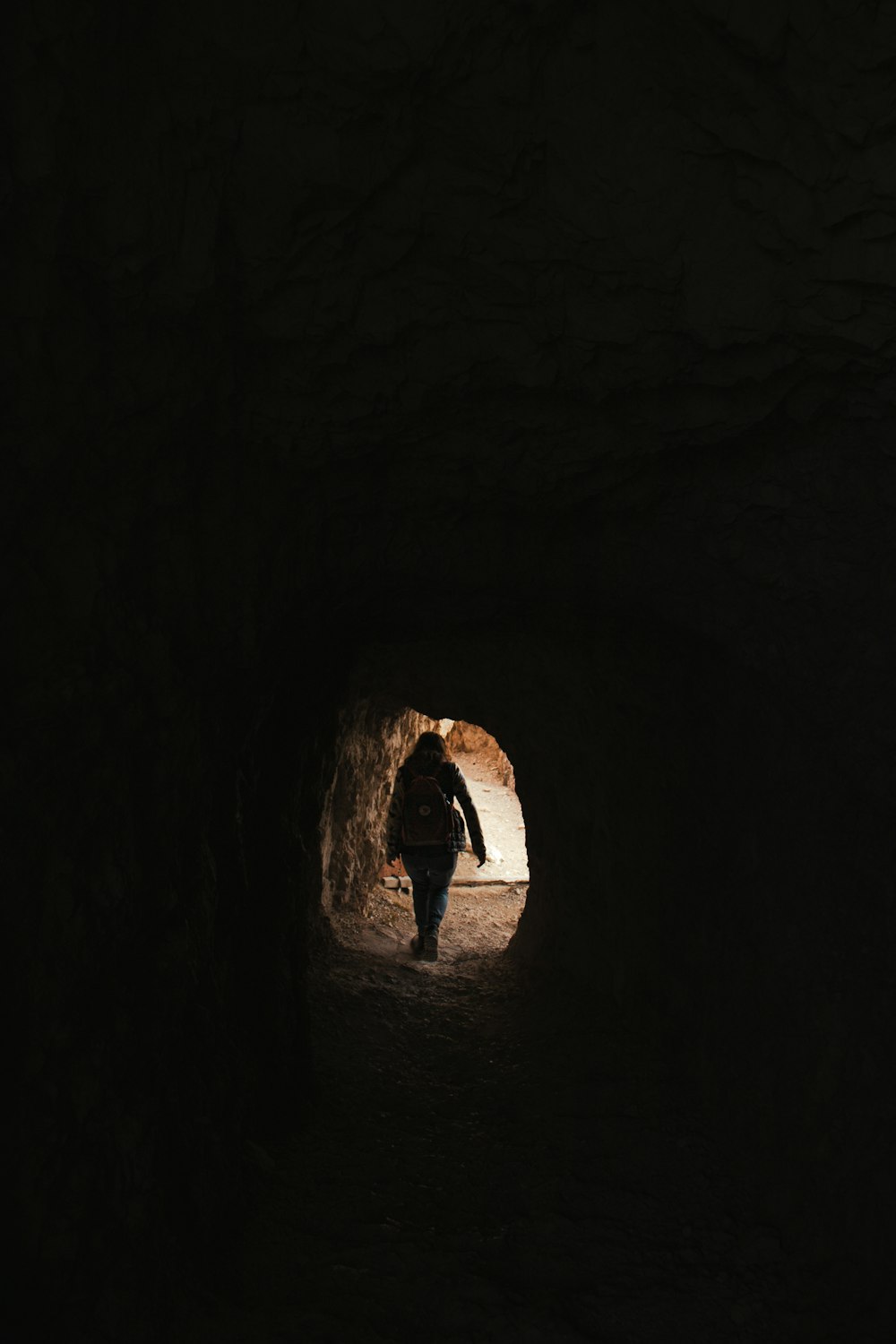 a person walking out of a dark tunnel