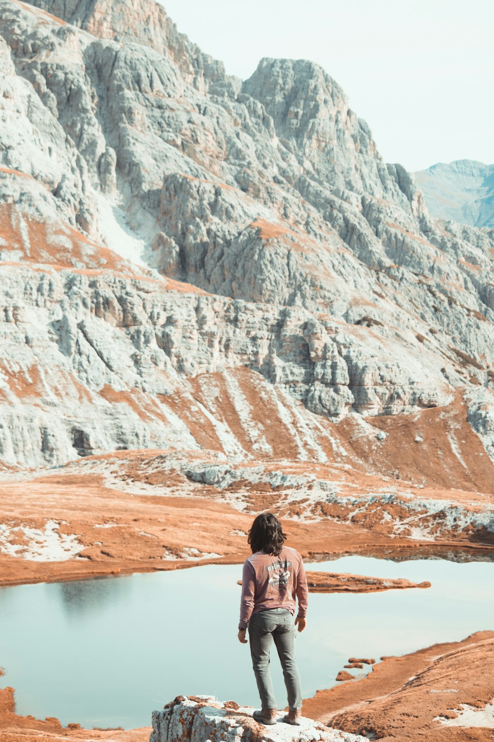 a person standing on a rock near a lake