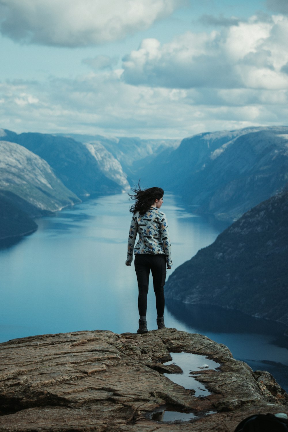 a woman standing on top of a cliff overlooking a body of water