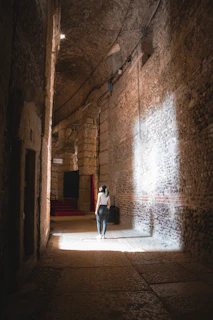 A dimly lit ancient temple corridor with subtle glowing symbols blending Guarani and Egyptian motifs on dark stone walls.