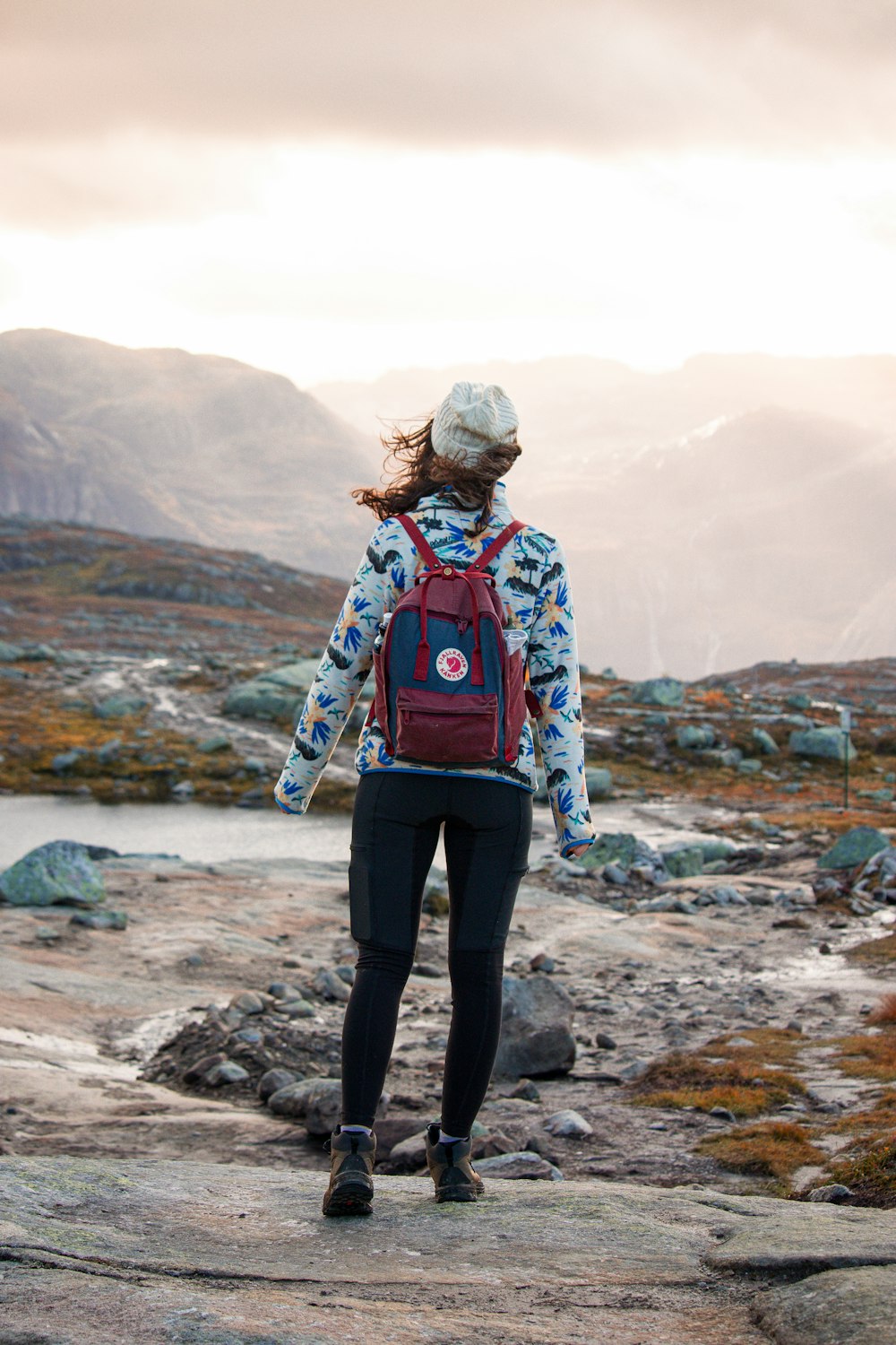 a woman with a backpack standing on a rock