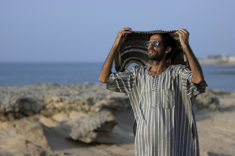 a man holding a bag over his head on the beach