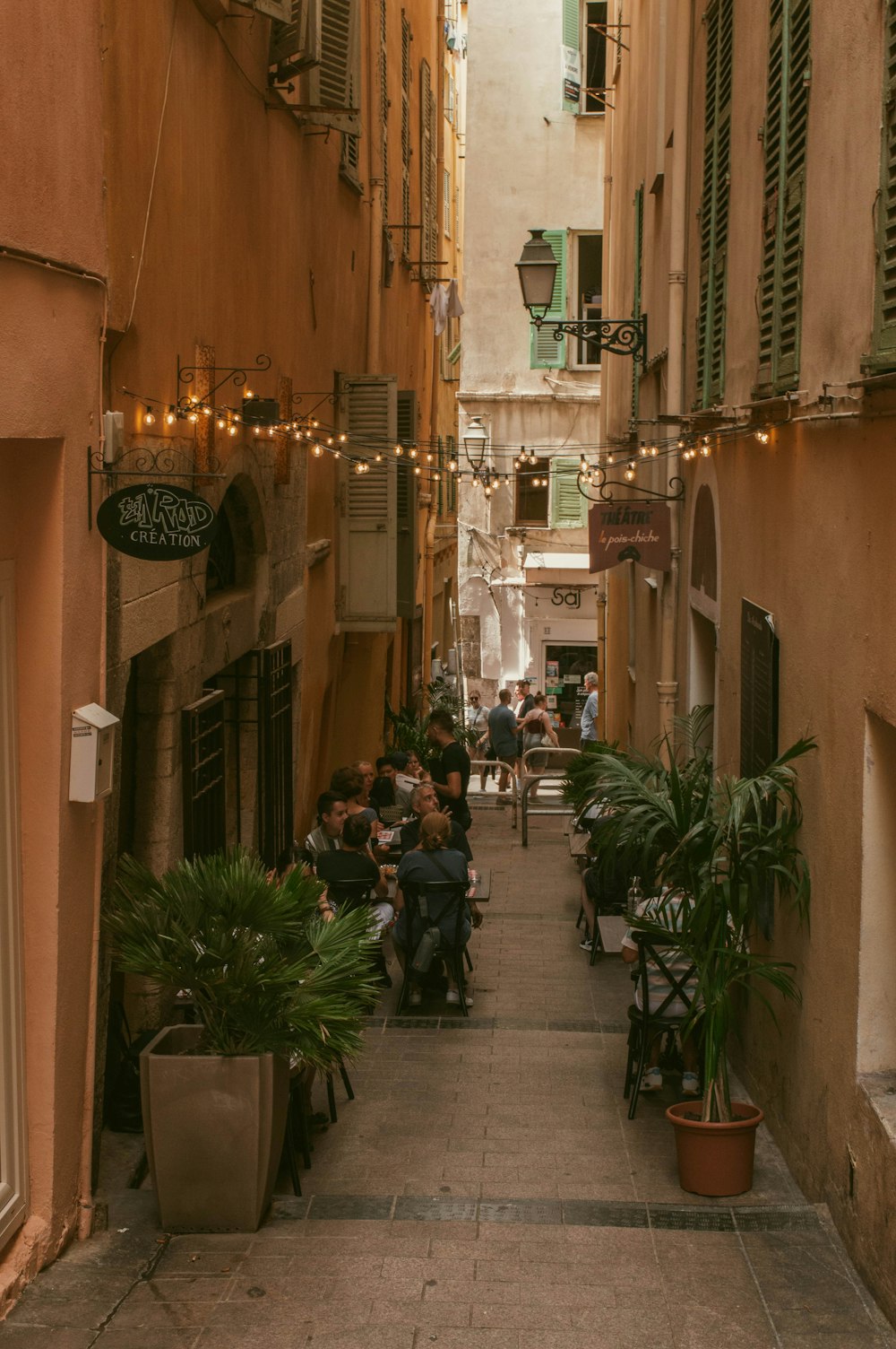 a narrow alley way with people sitting at tables