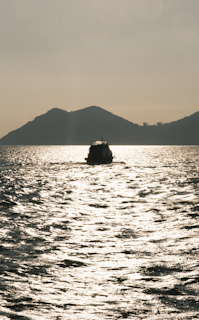 Early morning light shimmering on the calm waters as a boat sets out for trolling off the coast of Unawatuna.