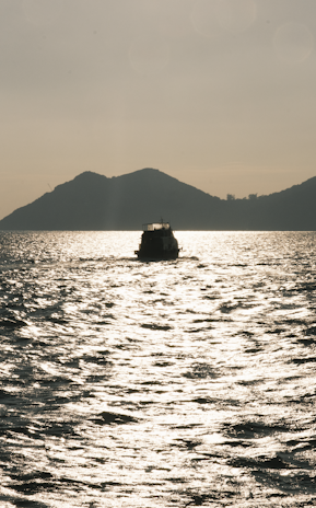Early morning light shimmering on the calm waters as a boat sets out for trolling off the coast of Unawatuna.