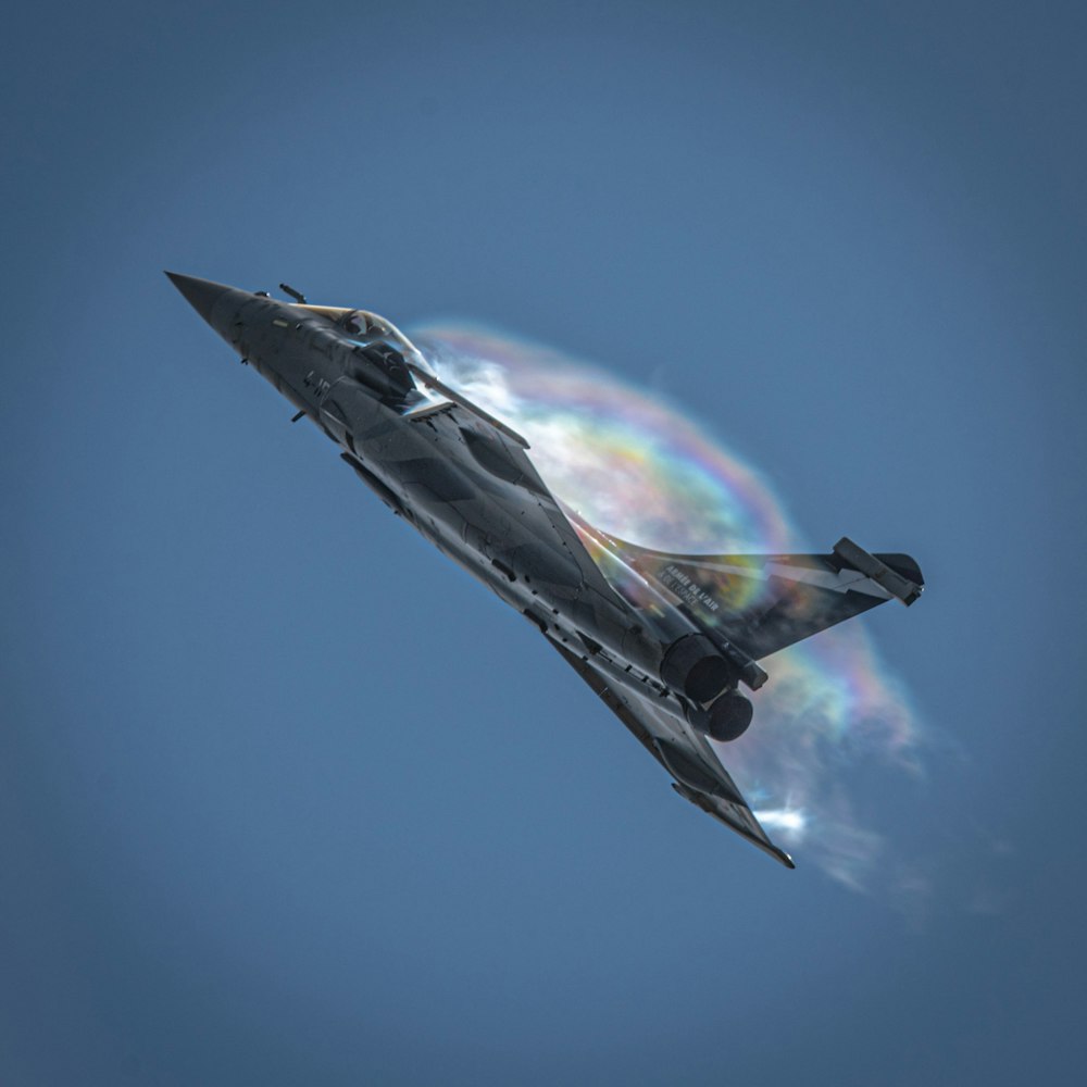 a fighter jet flying through a blue sky