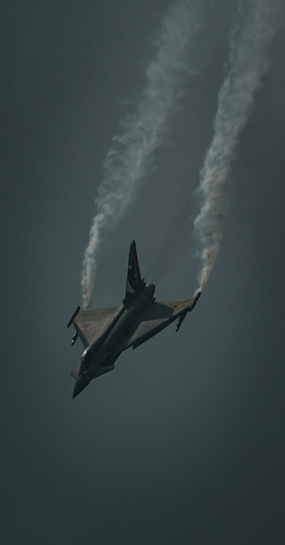 a fighter jet flying through a cloudy sky