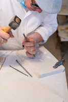 Artisan carefully carving a marble vase, surrounded by bright marble pieces in a sunlit workshop