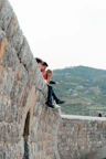 a group of people sitting on top of a stone wall