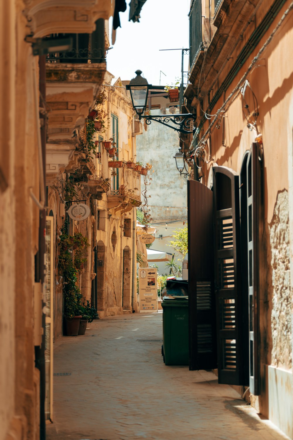 a narrow alley way with a green trash can