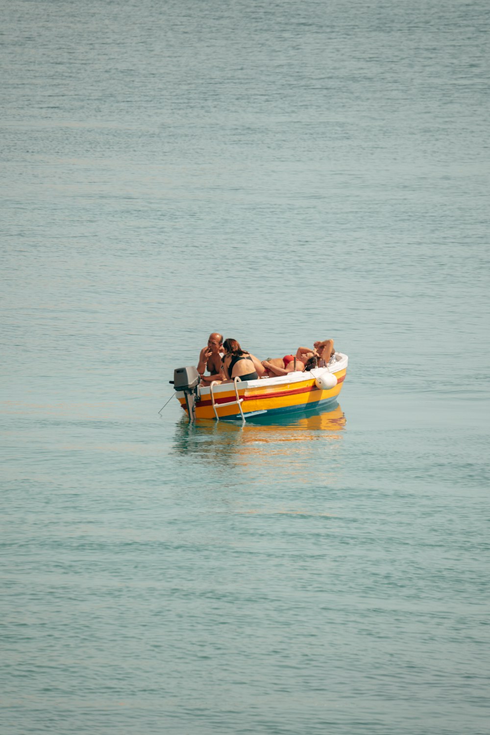 a group of people riding on the back of a yellow and blue boat