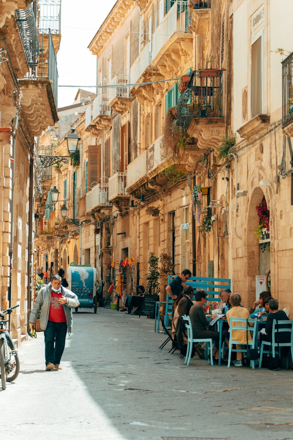 a group of people sitting at tables in an alleyway