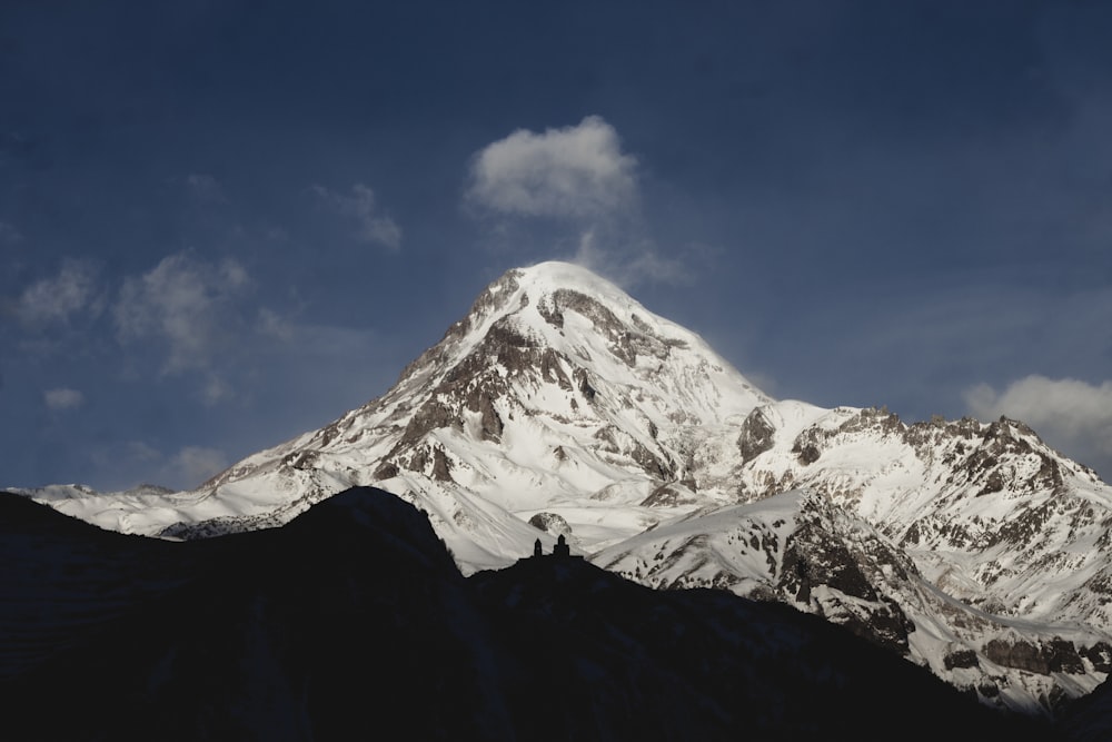 ein schneebedeckter Berg mit Wolken im Hintergrund