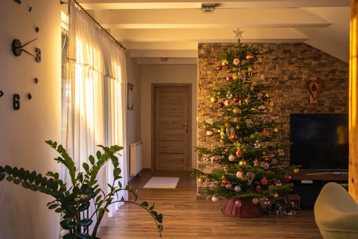 A warmly lit living room adorned with Christmas wreaths, twinkling lights, and a decorated tree.