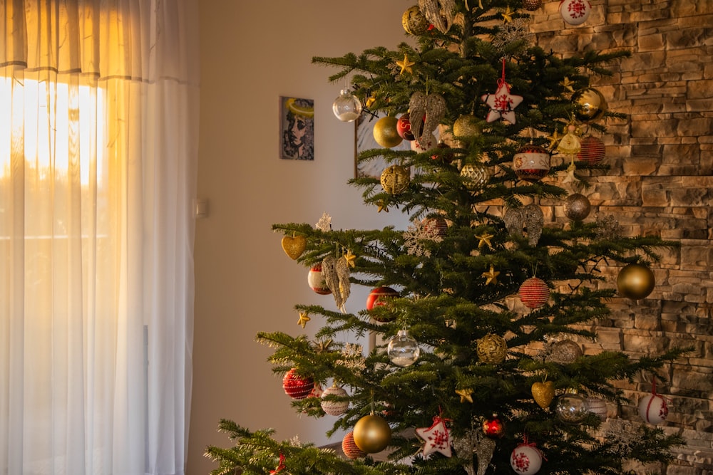 a decorated christmas tree in front of a brick wall