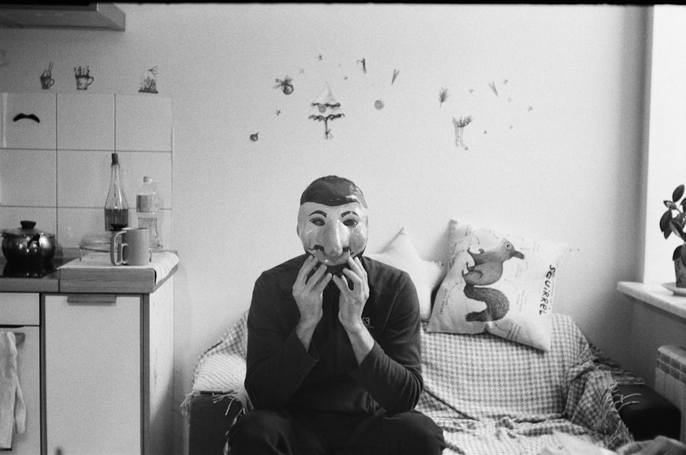 a man sitting on a bed with a mask on his face