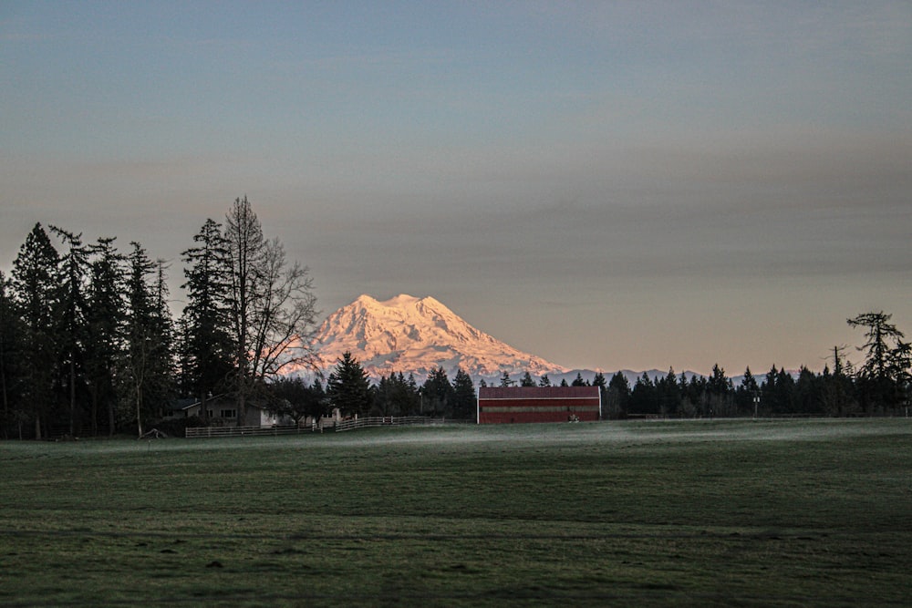 a field with a barn and a mountain in the background