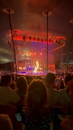 A vibrant circus tent with performers practicing acrobatics under colorful lights.
