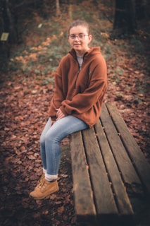 A cozy scene featuring a person wearing a soft cotton t-shirt and jeans, sitting on a park bench with autumn leaves around.
