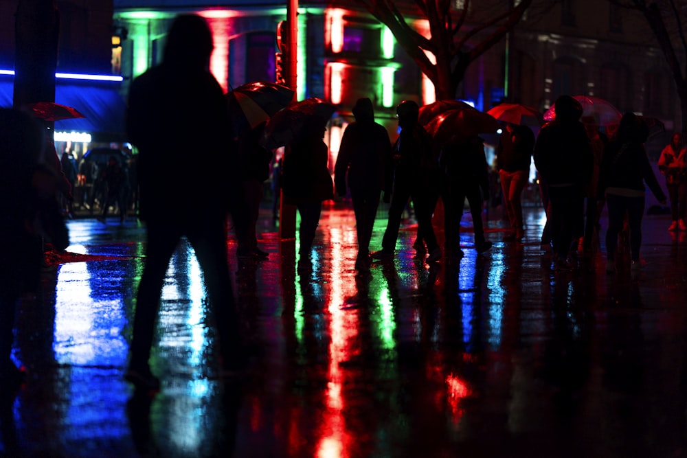 a group of people walking down a street at night