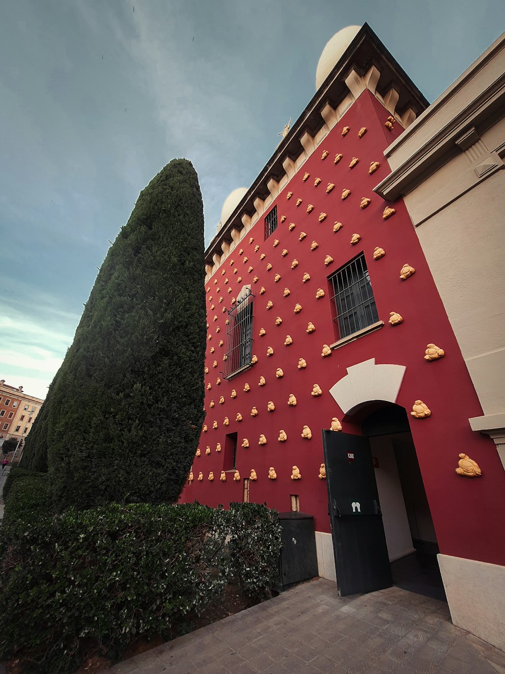 a tall red building with a tree next to it