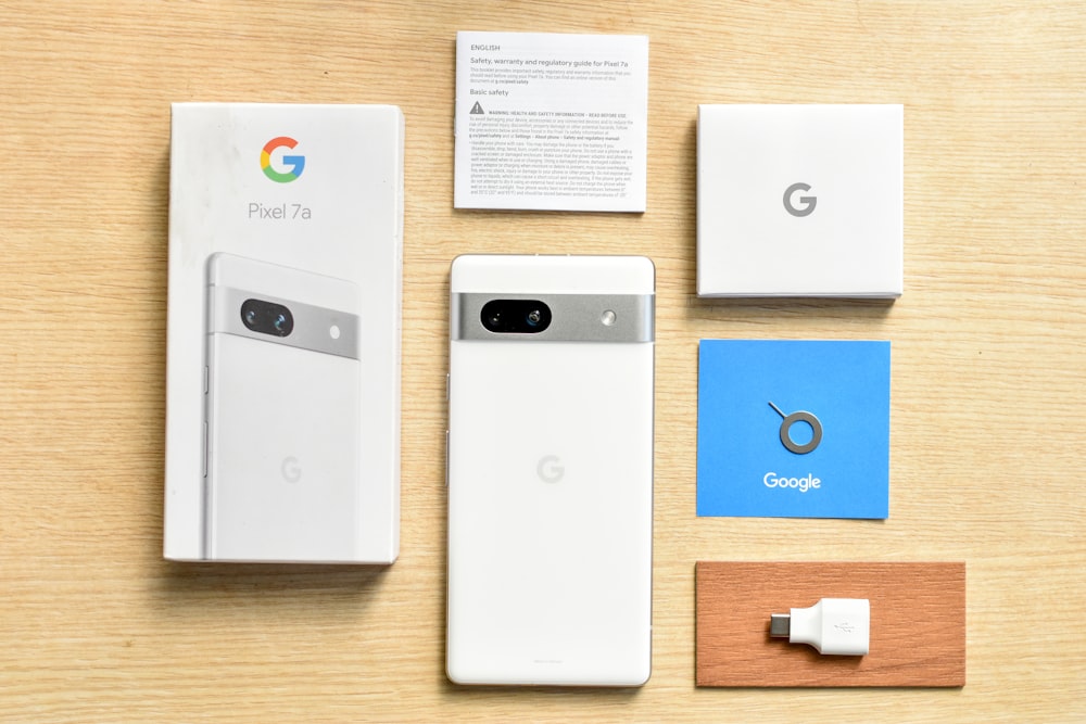 a white google phone sitting next to a box and a charger