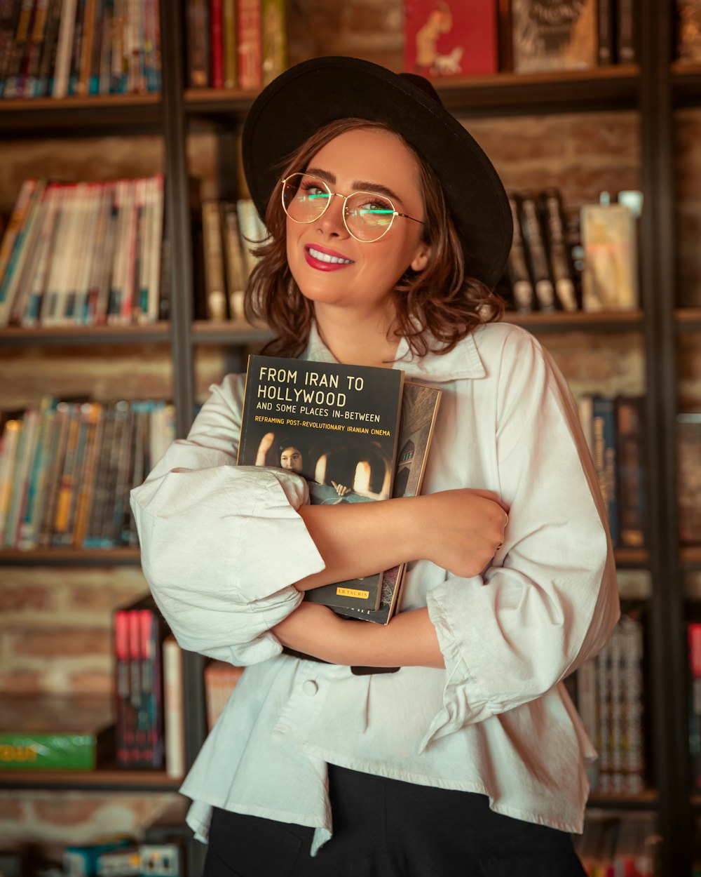 a woman wearing glasses and a hat holding a book