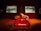 A surreal art installation featuring a large red sofa resembling lips, a structure resembling a human nose above it, and two framed artworks in the background. The room has wooden flooring and a dark, atmospheric lighting.