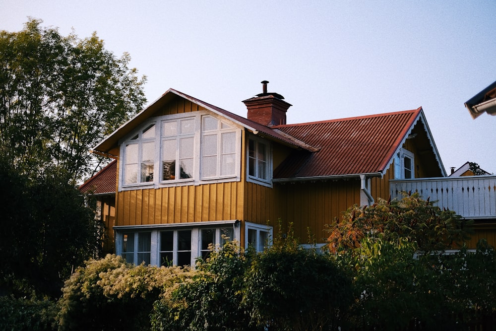 a yellow house with a red roof and white windows