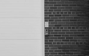 A video door phone mounted beside a front door, showing a clear visitor image.