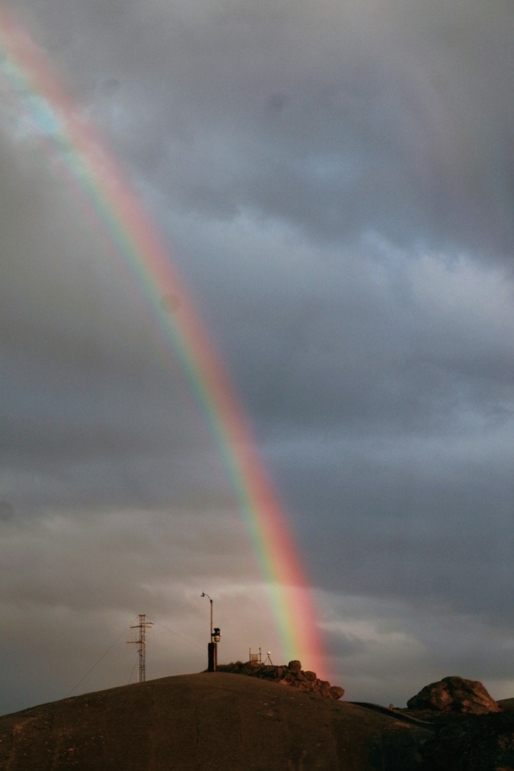 a rainbow is shining in the sky over a hill