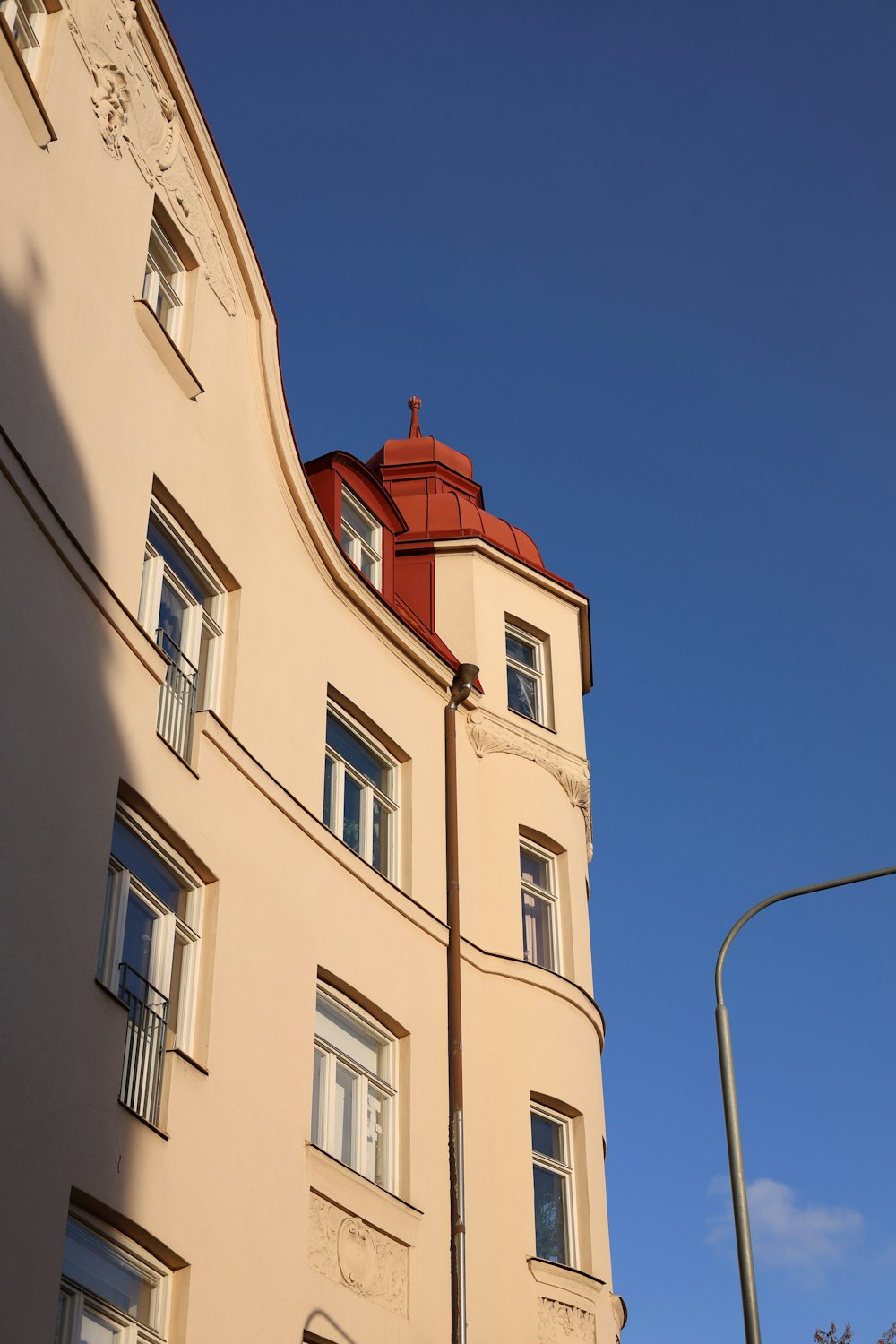 a tall building with a red roof next to a street light