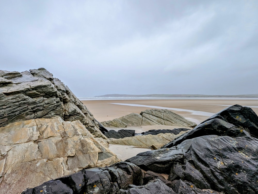 a rock formation on a beach with a cloudy sky in the background