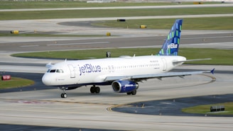 A JetBlue airplane taxiing on a runway under a clear sky