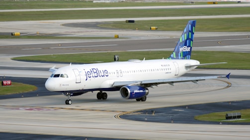 A JetBlue airplane taxiing on a runway under a clear sky